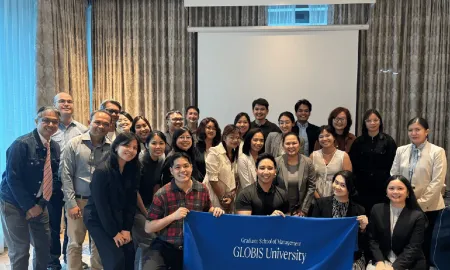 Attendees gathered behind a GLOBIS University banner at the close of the party