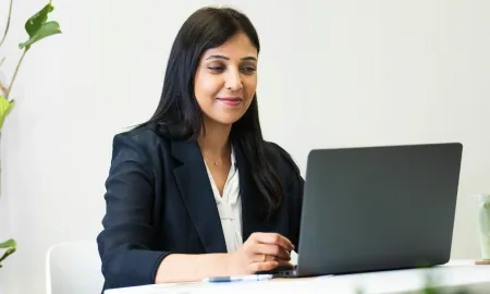 A female business school student engaging in online coursework on a laptop.