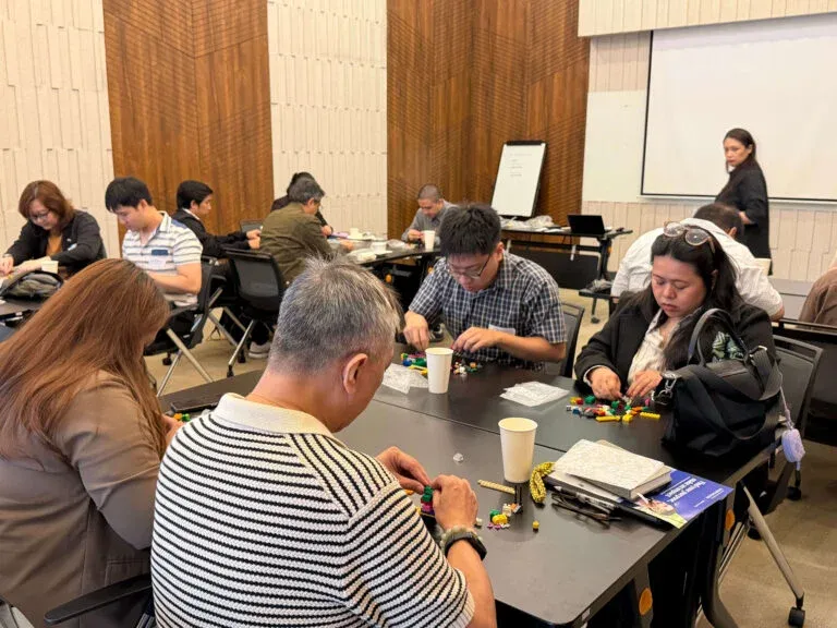 Participants at tables building small models from plastic bricks.