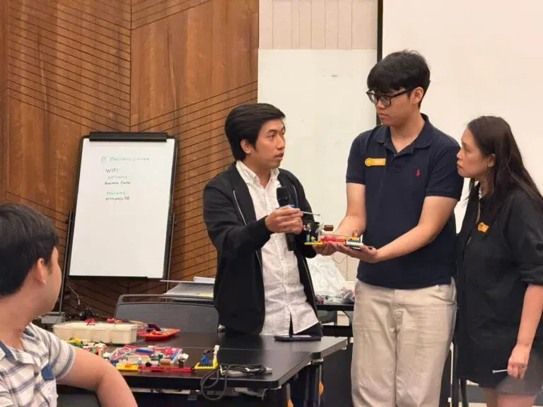 Speaker with a microphone discussing a participant's brick model with the group.