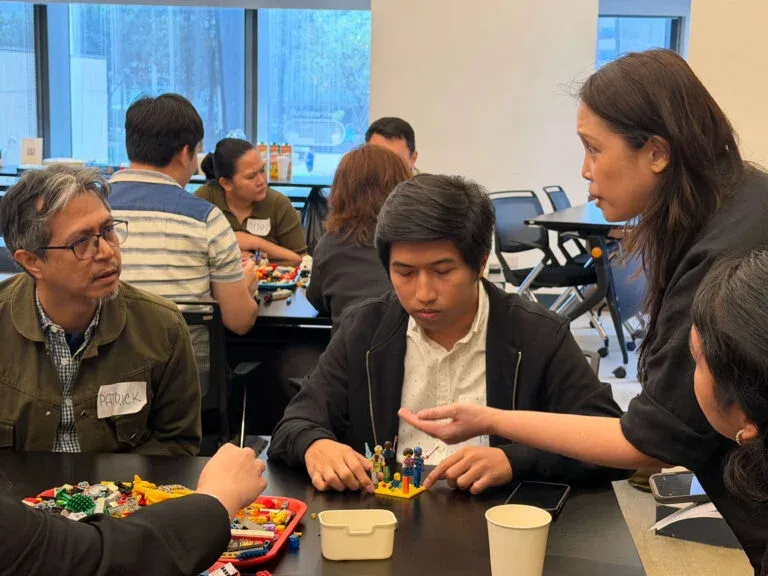 Participants discussing a completed brick model of figures at their table.