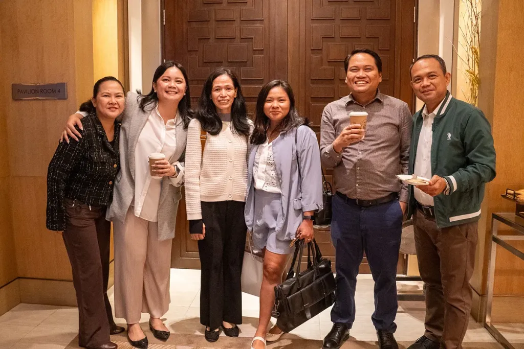 Six business school students smiling and posing together during a networking break