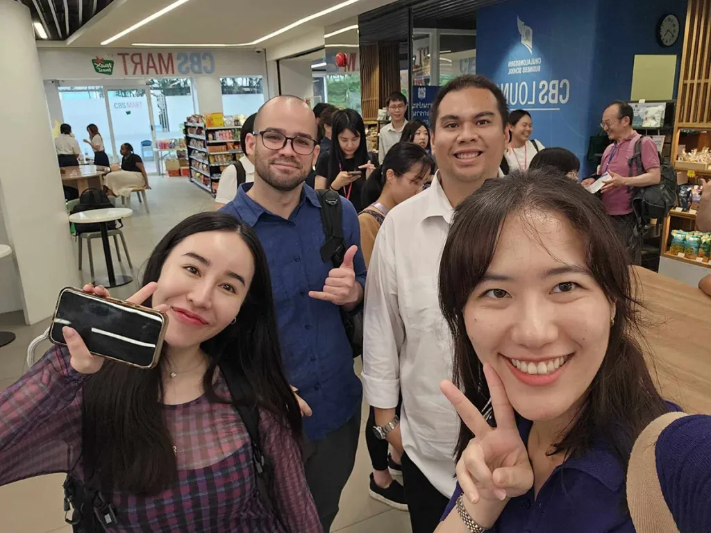Four business school students taking a smiling selfie together inside a CBS campus building.