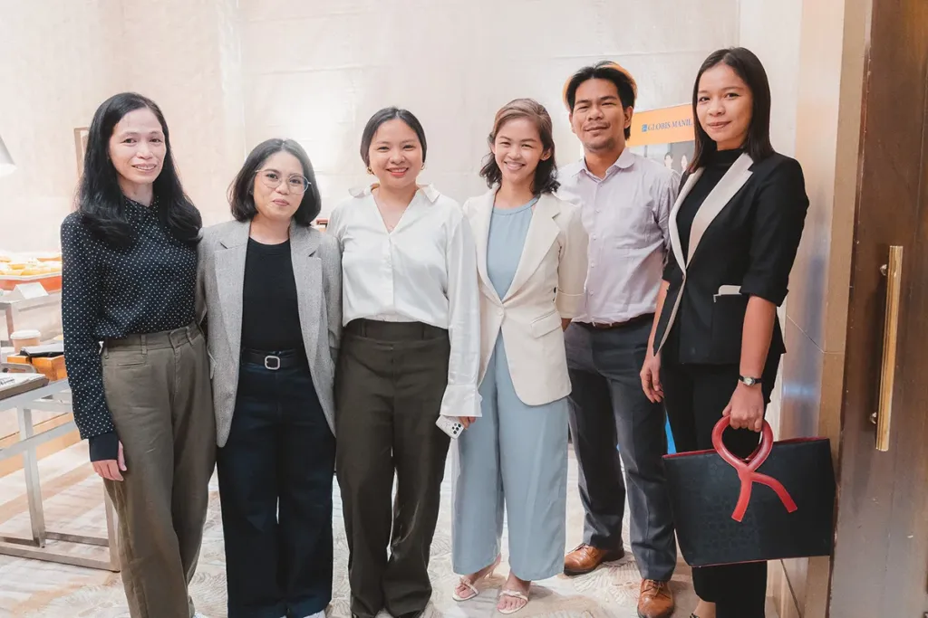 Six Pre-MBA students in professional attire smiling and posing together.