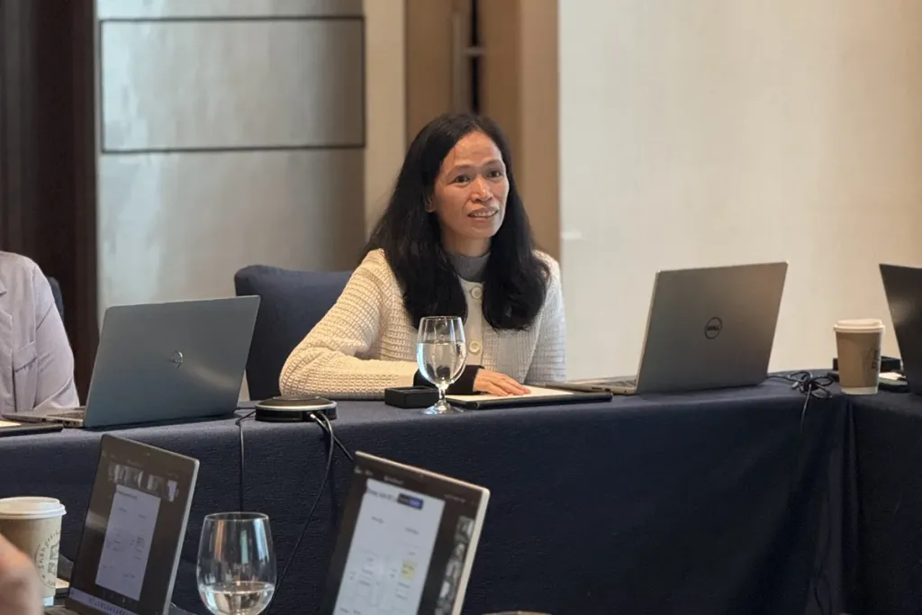 A female student at a table with an open laptop, listening attentively during a Pre-MBA class.